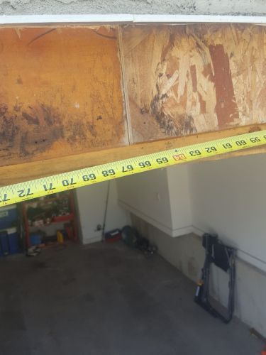 A tape measure is being used to measure a door in a garage.