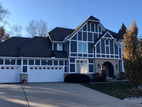 A large black and white house with two garage doors