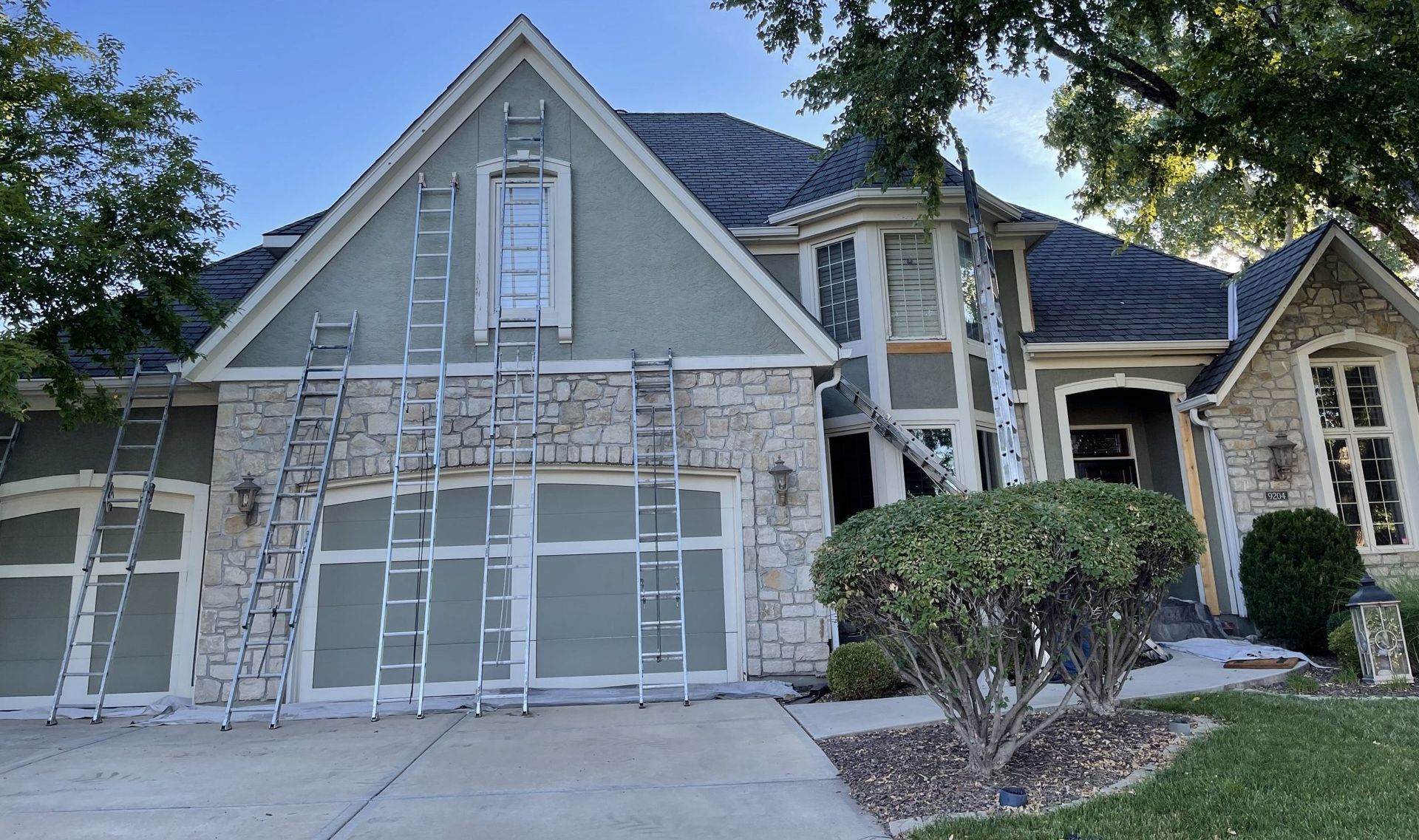 A house is being painted with ladders in front of it.
