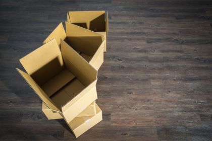 Three cardboard boxes are stacked on top of each other on a wooden floor.