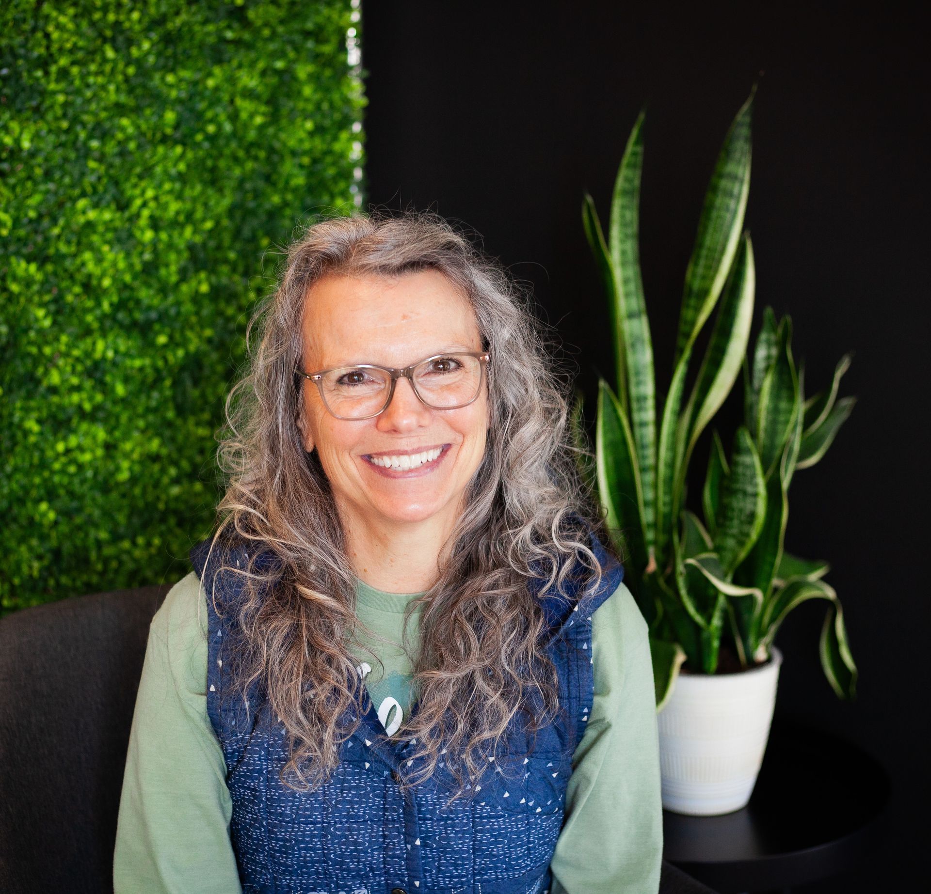 Woman with wavy, graying hair and glasses smiling