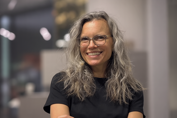 Woman with wavy, graying hair and glasses smiling
