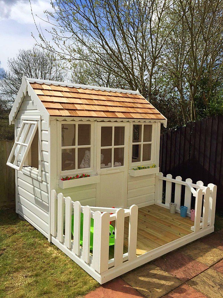 Wooden painted playhouse with slatted roof tiles windows and fence