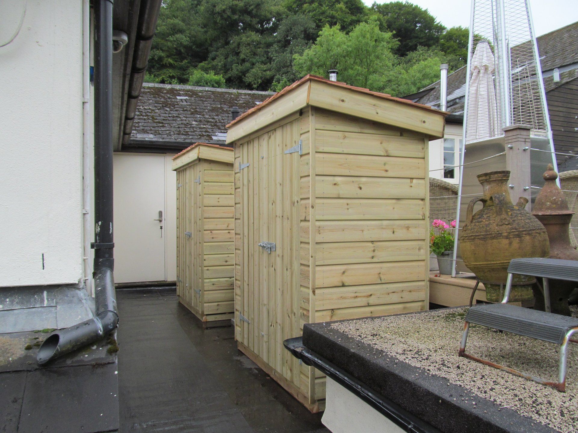 Two identical storage sheds side by side with double doors and no windows