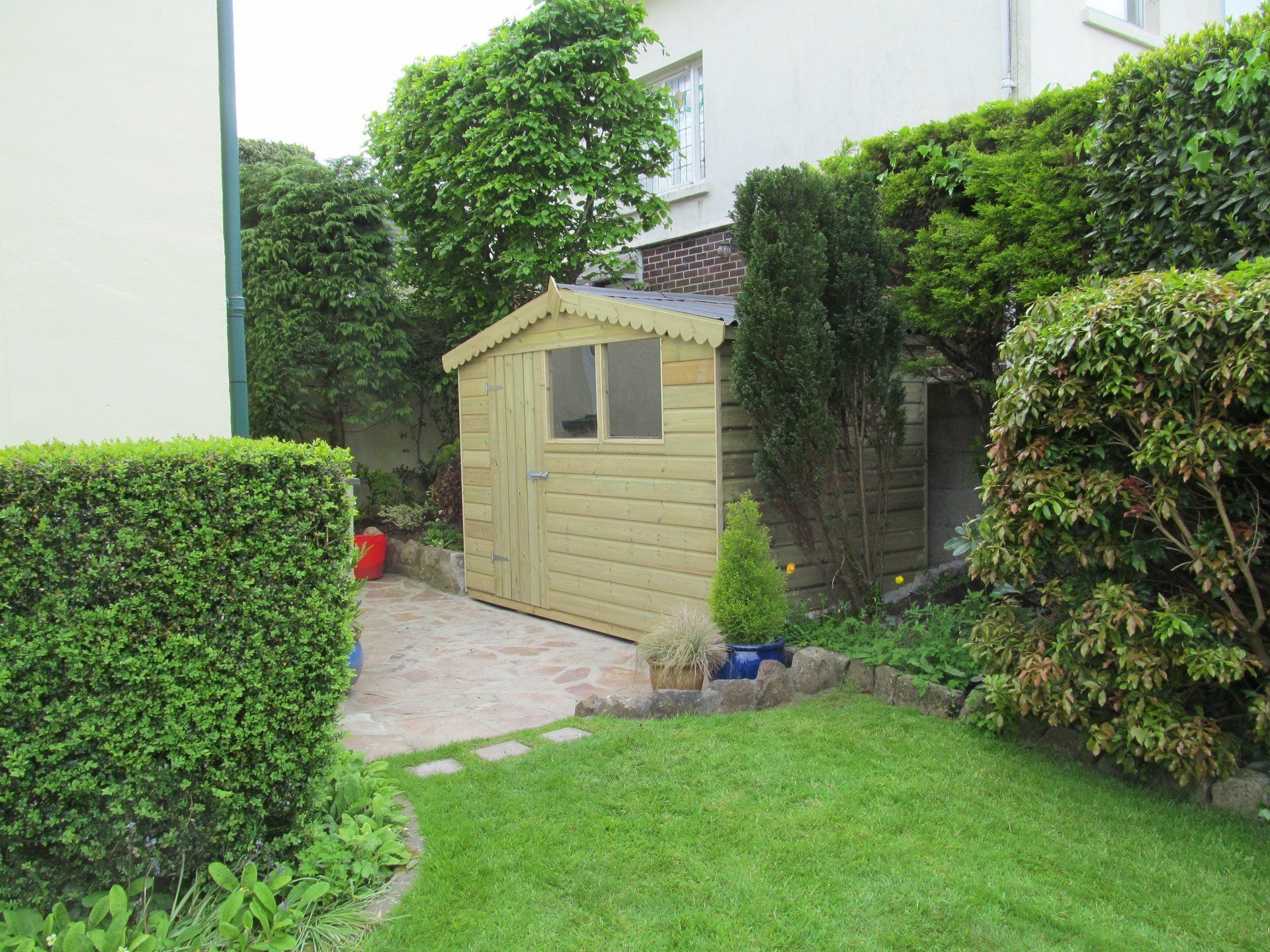 Cabin Shed against wall in garden with single door and double windows to the front
