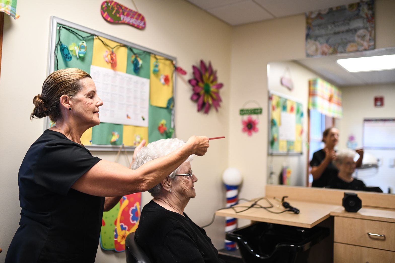 Caregiver assisting resident with hair care in Watson Assisted Living salon