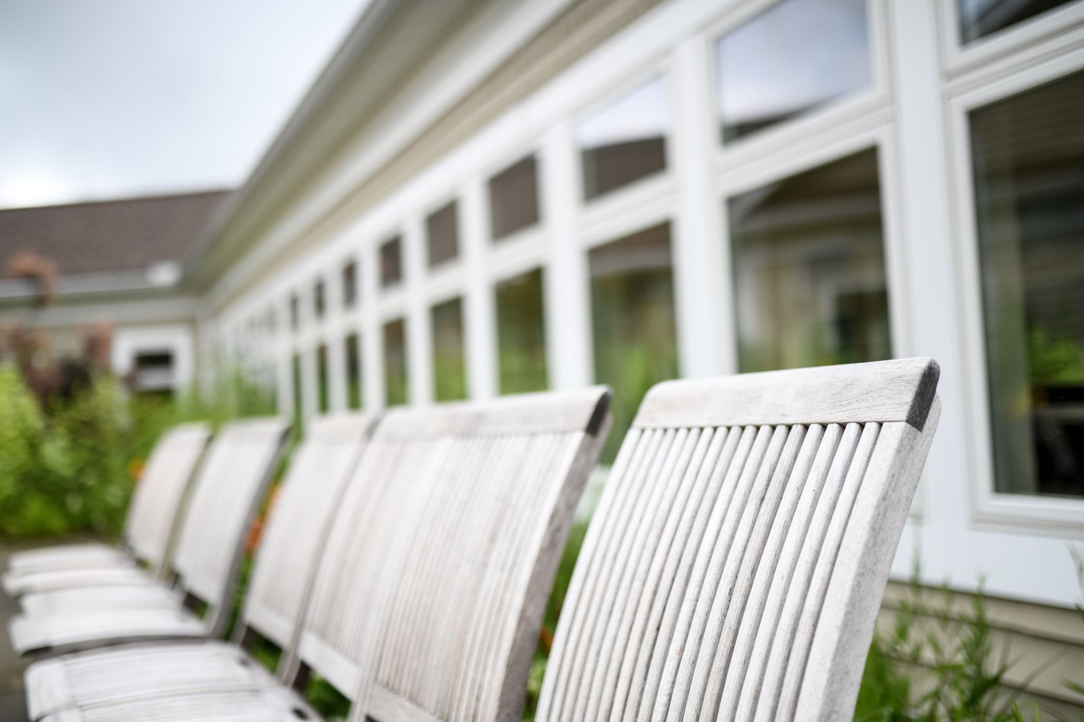 White rocking chairs lined up outside Watson Assisted Living overlooking the courtyard