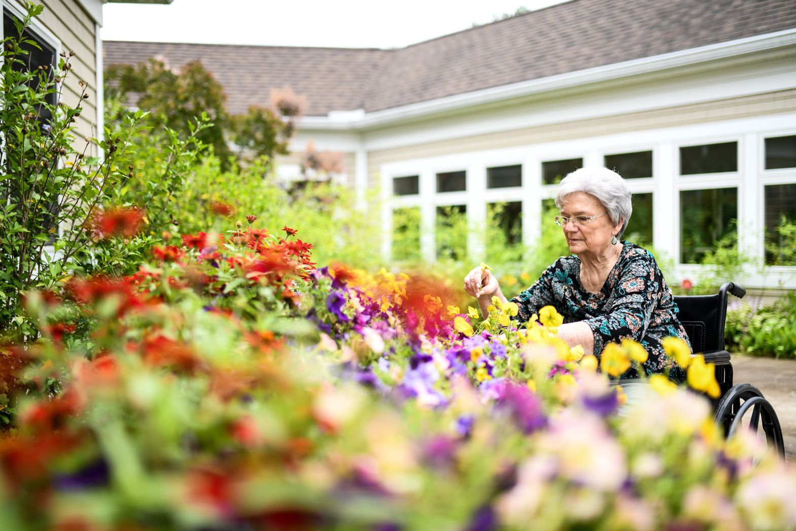 Elderly woman gardening outdoors with caregiver at Watson Assisted Living