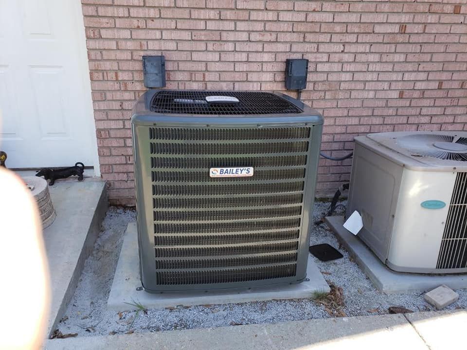 Two air conditioners are sitting outside of a brick building.
