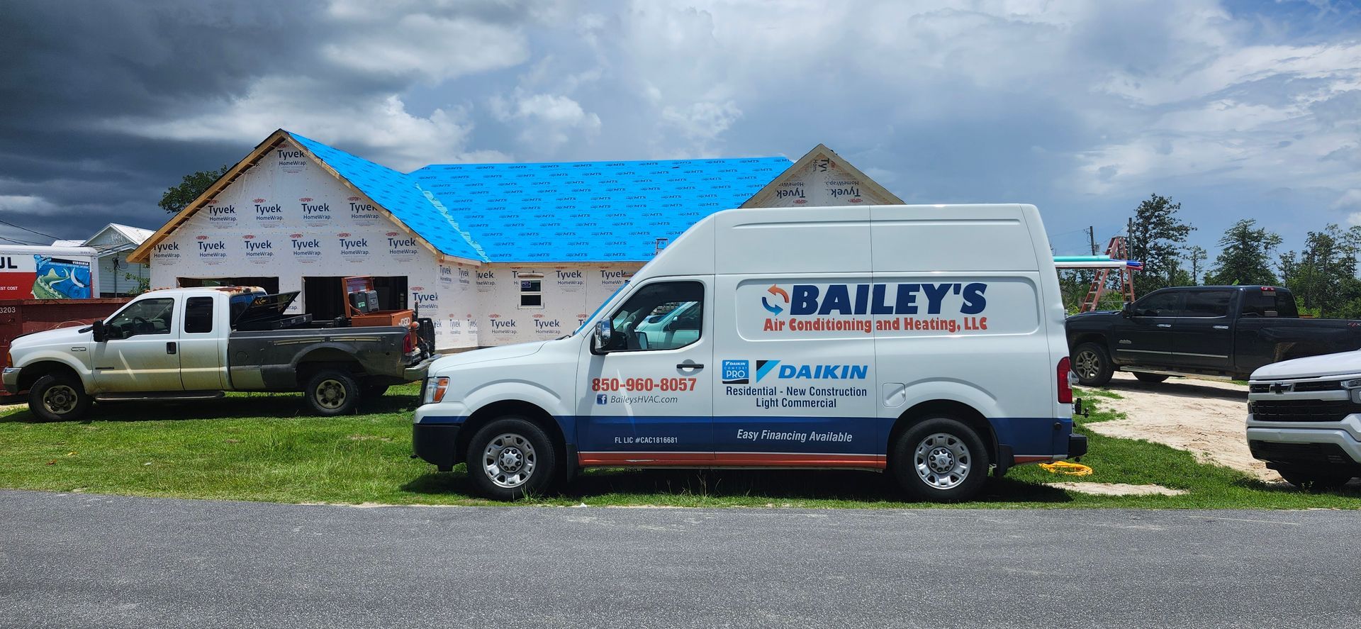 A bailey 's van is parked in front of a house under construction.