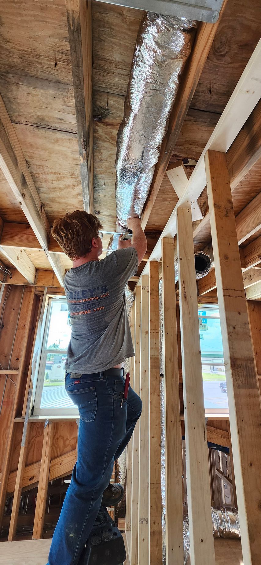 A woman is standing on a ladder in a house under construction.