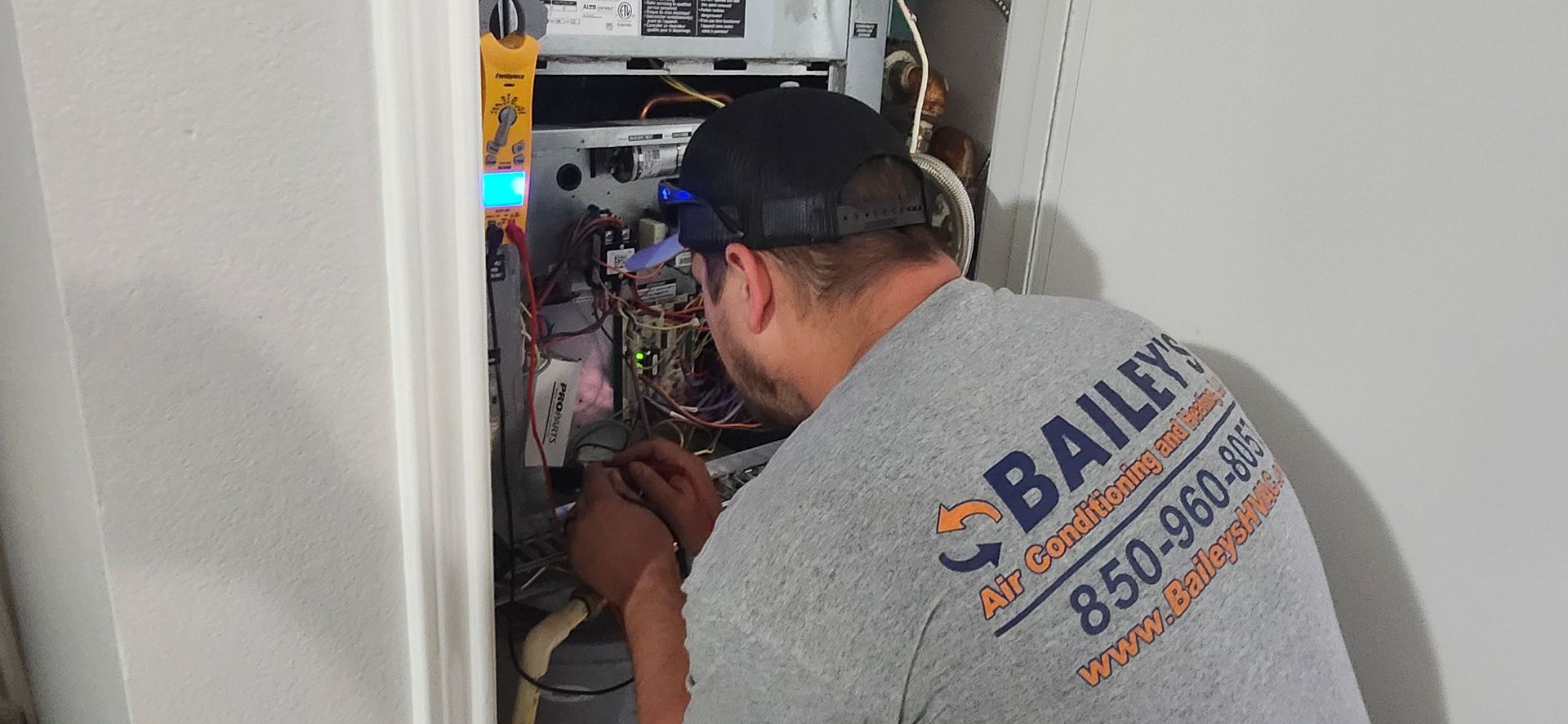 A man is working on a heating system in a closet.