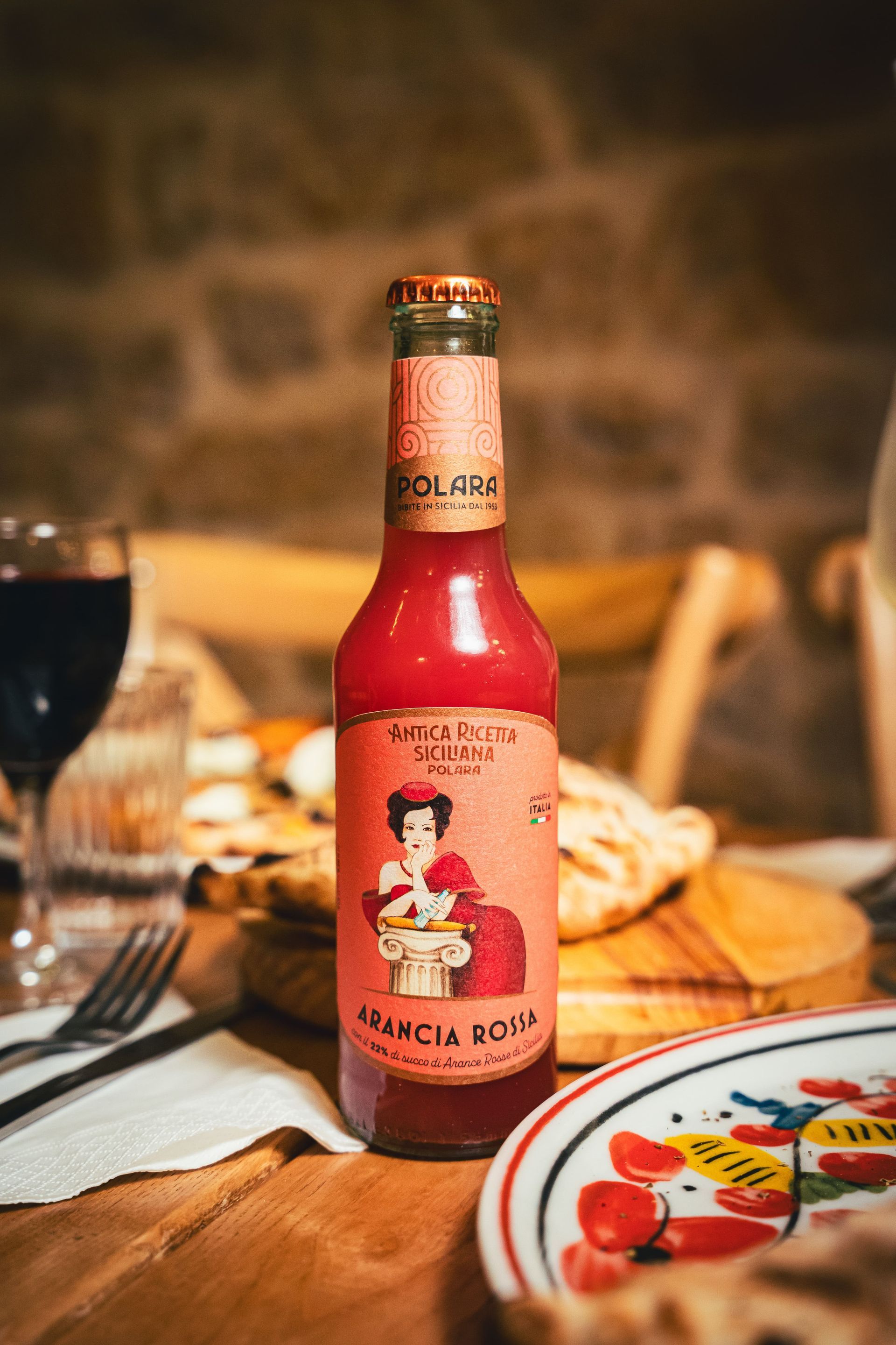 Bouteille de boisson Arancia Rossa sur une table dressée pour le repas.