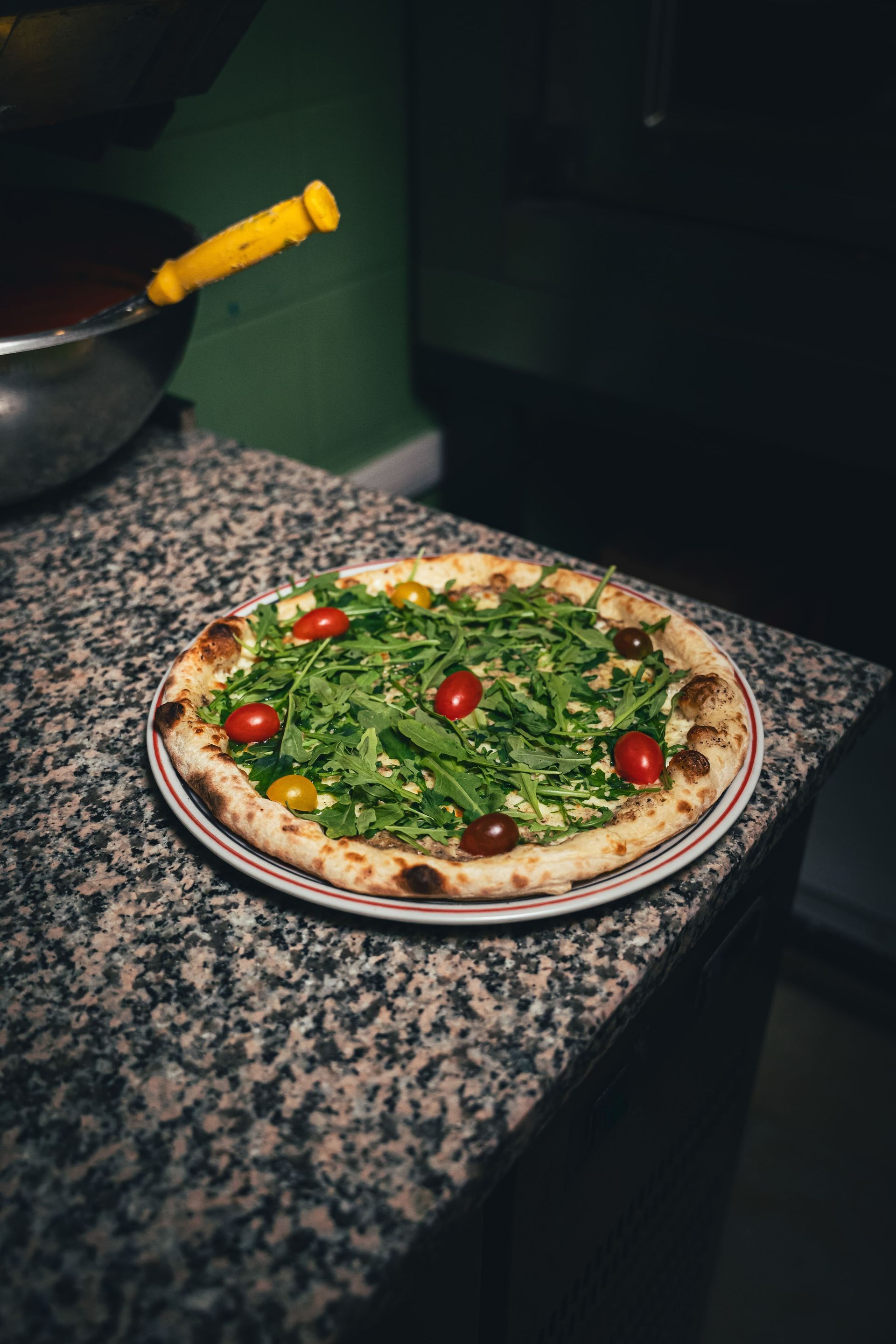 Pizza à la roquette et aux tomates cerises sur un comptoir moucheté.