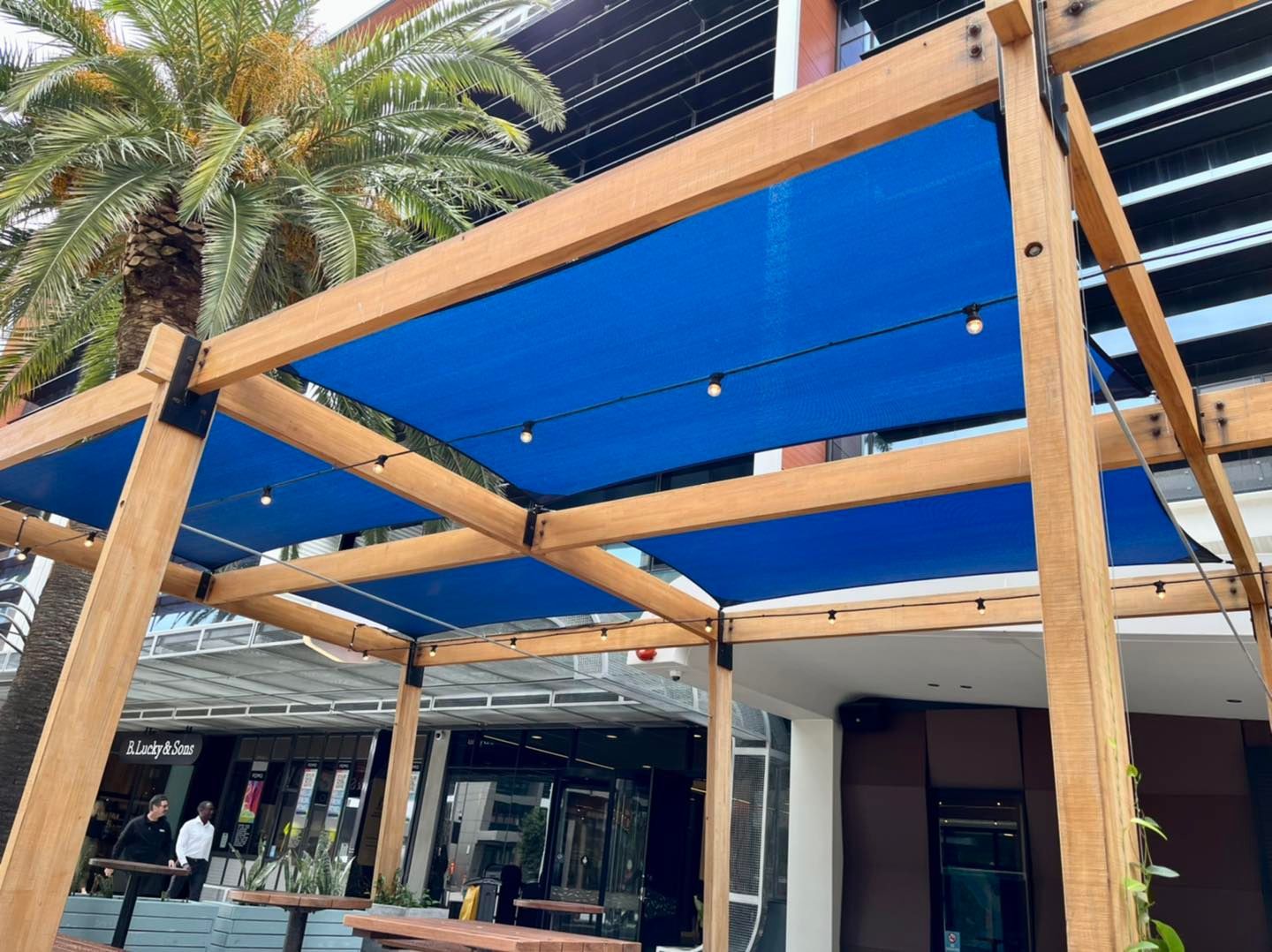 A blue awning is hanging from a wooden structure in front of a building.
