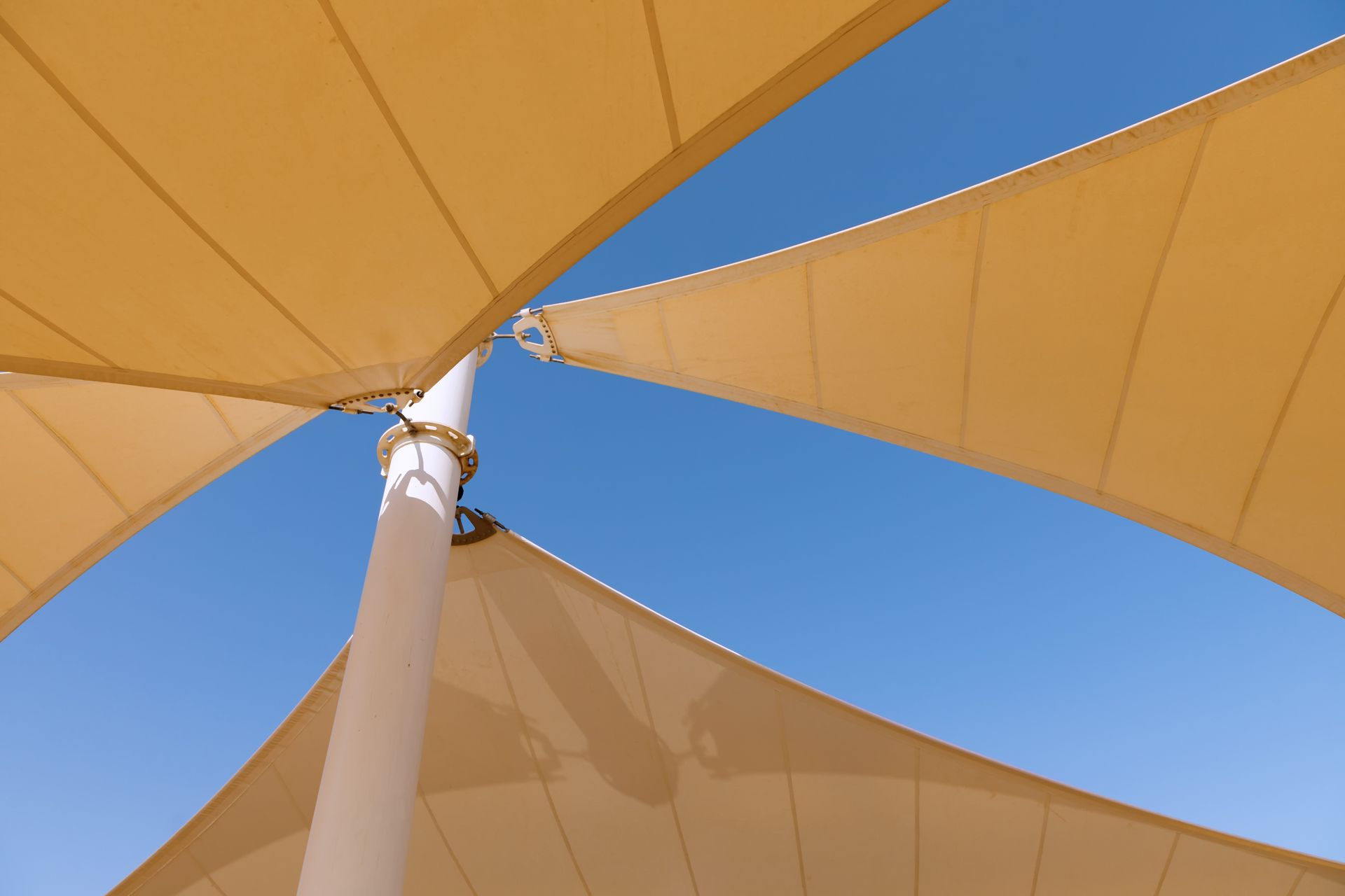 Close-up of yellow shade sail against bright sky.
