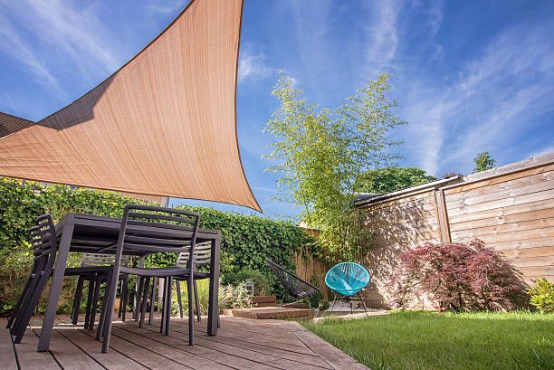 A modern house terrace in summer with a table and a sun sail.