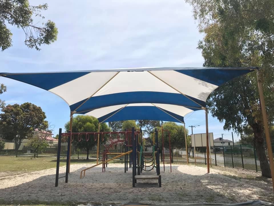 A playground with a blue and white shade over it.