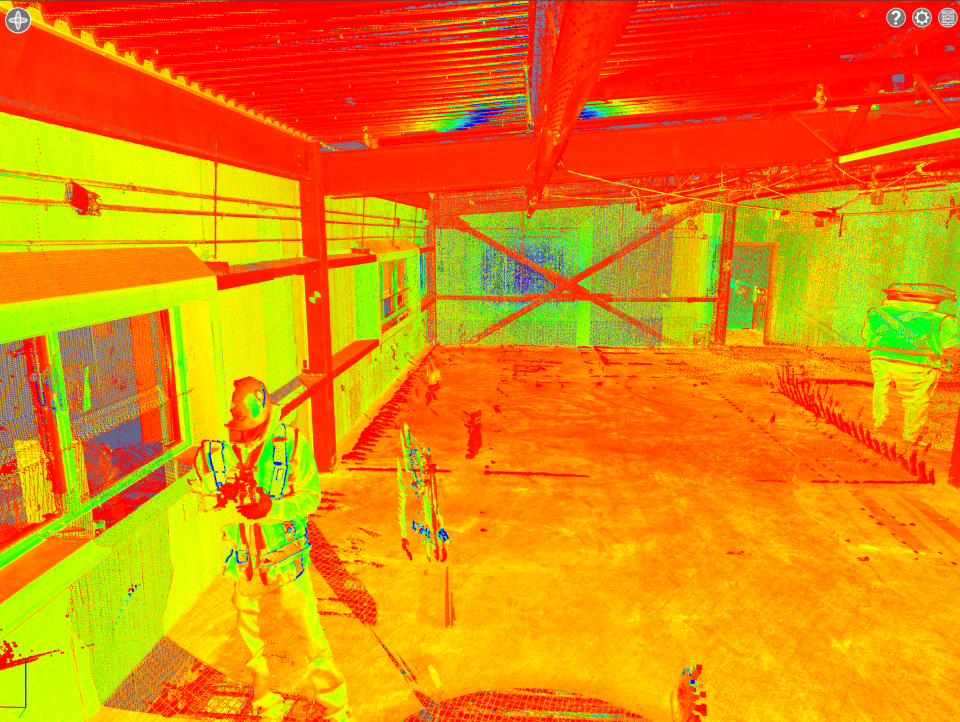 Une image thermique montrant une personne debout dans un bâtiment industriel fortement éclairé, avec des poutres métalliques structurelles.