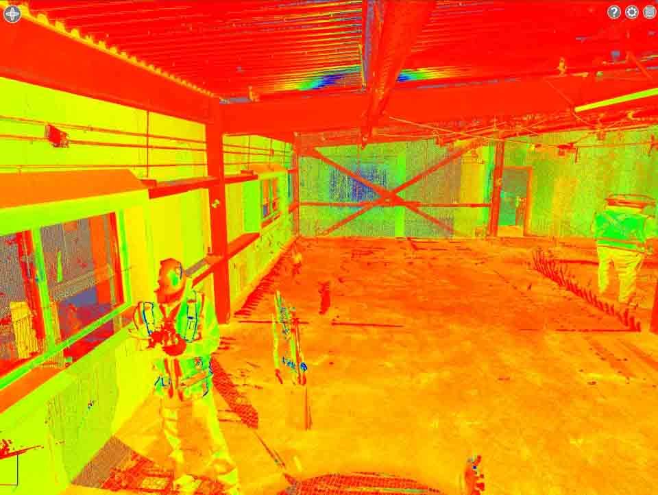 Une image thermique montrant une personne debout dans un bâtiment industriel fortement éclairé, avec des poutres métalliques structurelles.