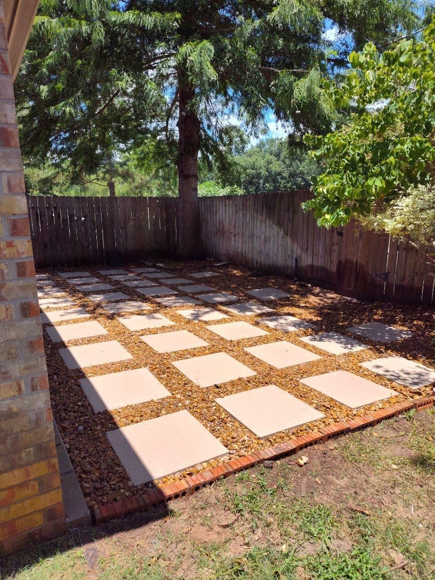 Stone patio with square pavers, gravel, and a wooden fence.