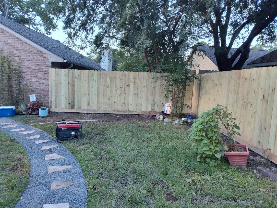 Backyard with a gravel path, new wooden fence, grass, a generator, and plants.