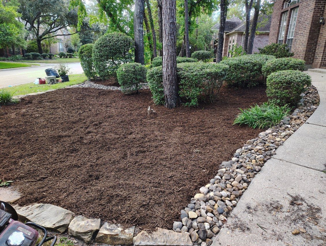 Front yard landscaping with mulch, shrubs, and a stone border.