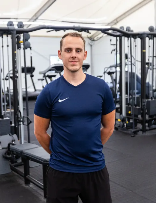 Een man in een blauw Nike-shirt staat in een sportschool.