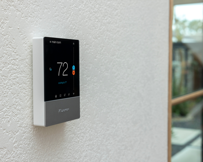 A thermostat is hanging on a white wall and the temperature is 72 degrees