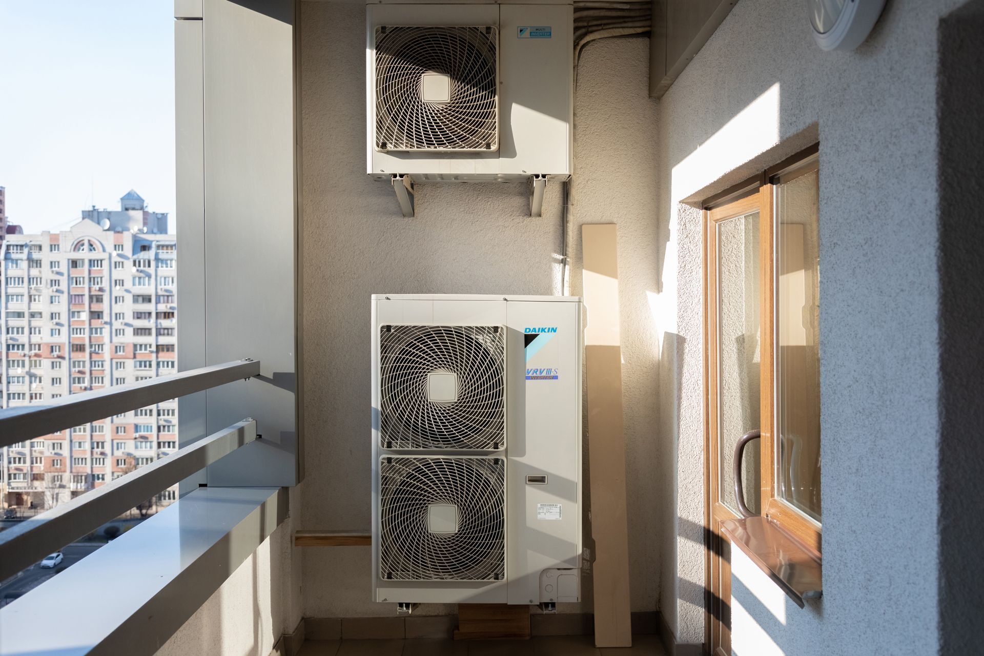 Two Air Conditioners Are Mounted on the Side of a Building on a Balcony