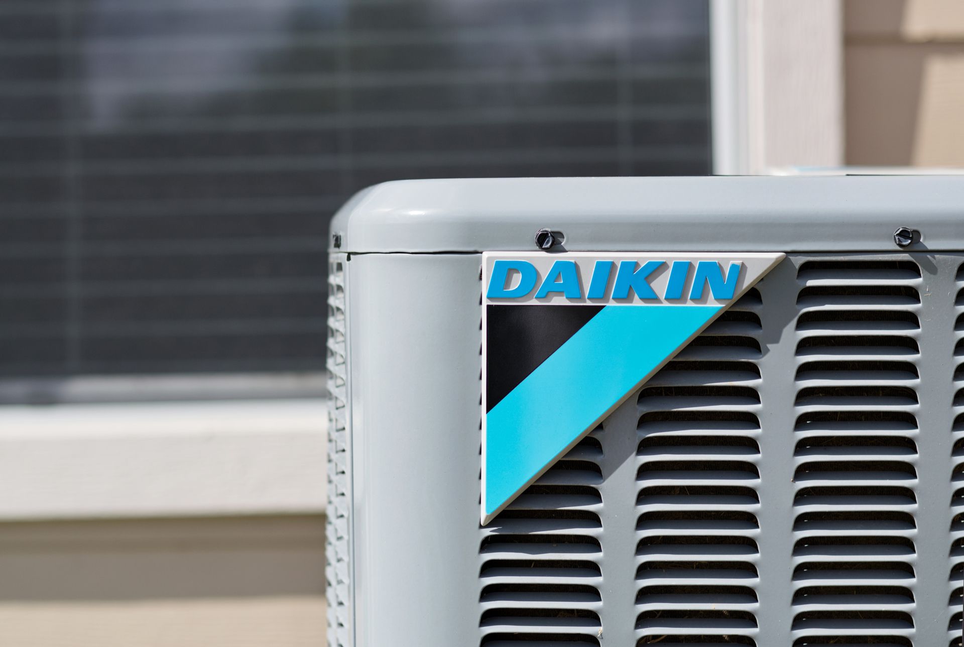 A daikin air conditioner is sitting in front of a window.