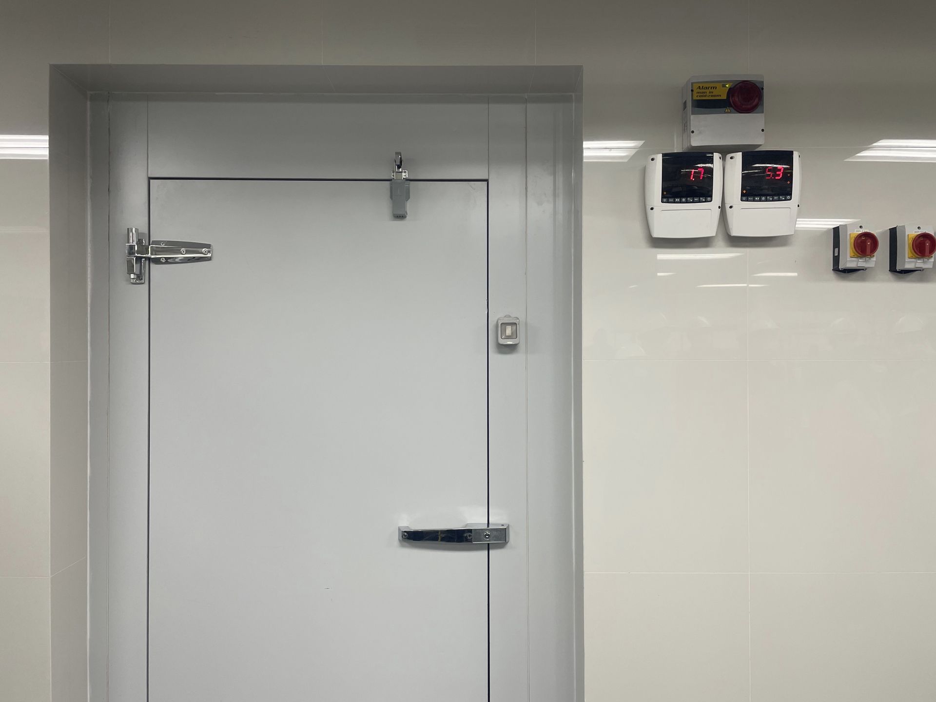 A white door in a room with a fire alarm on the wall