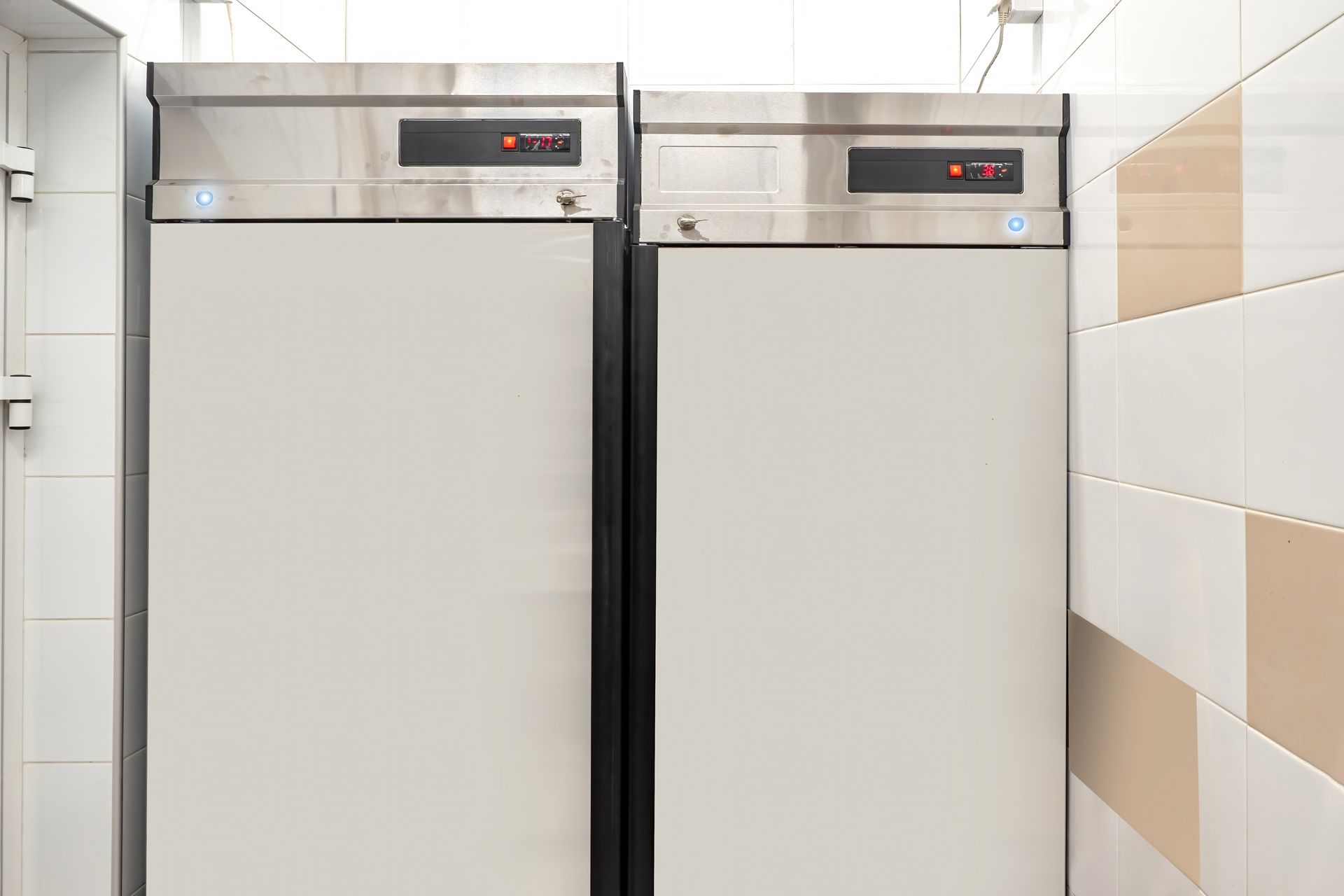 Two refrigerators are sitting next to each other in a kitchen