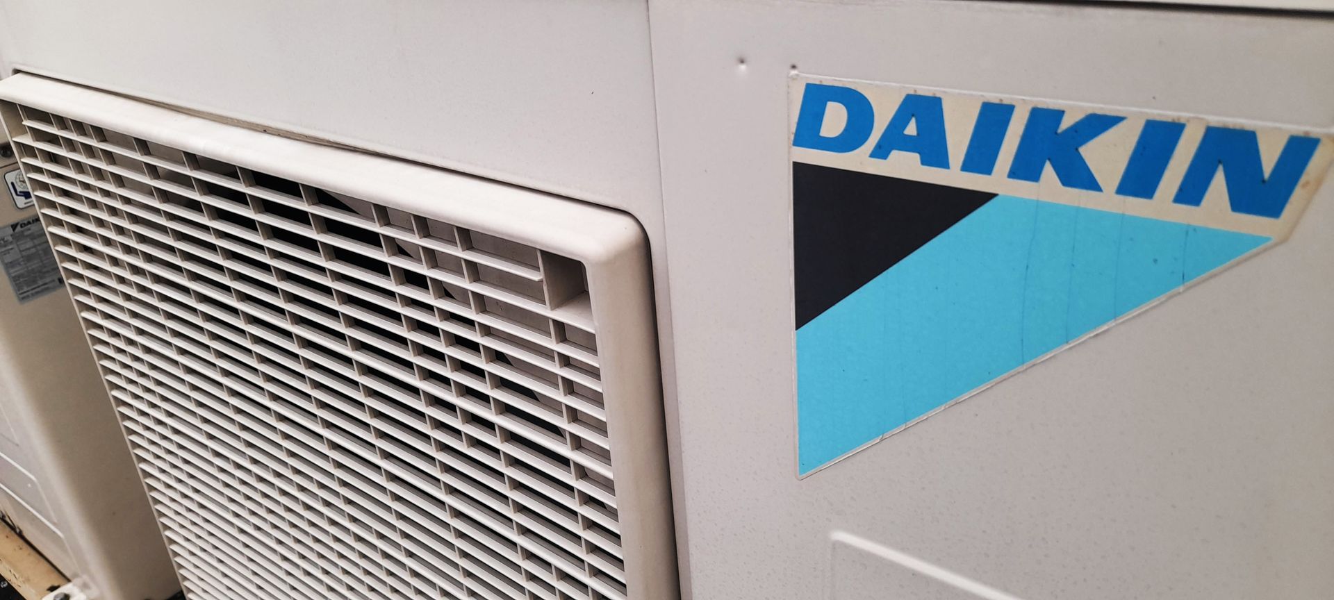 A daikin air conditioner is sitting on a white wall.