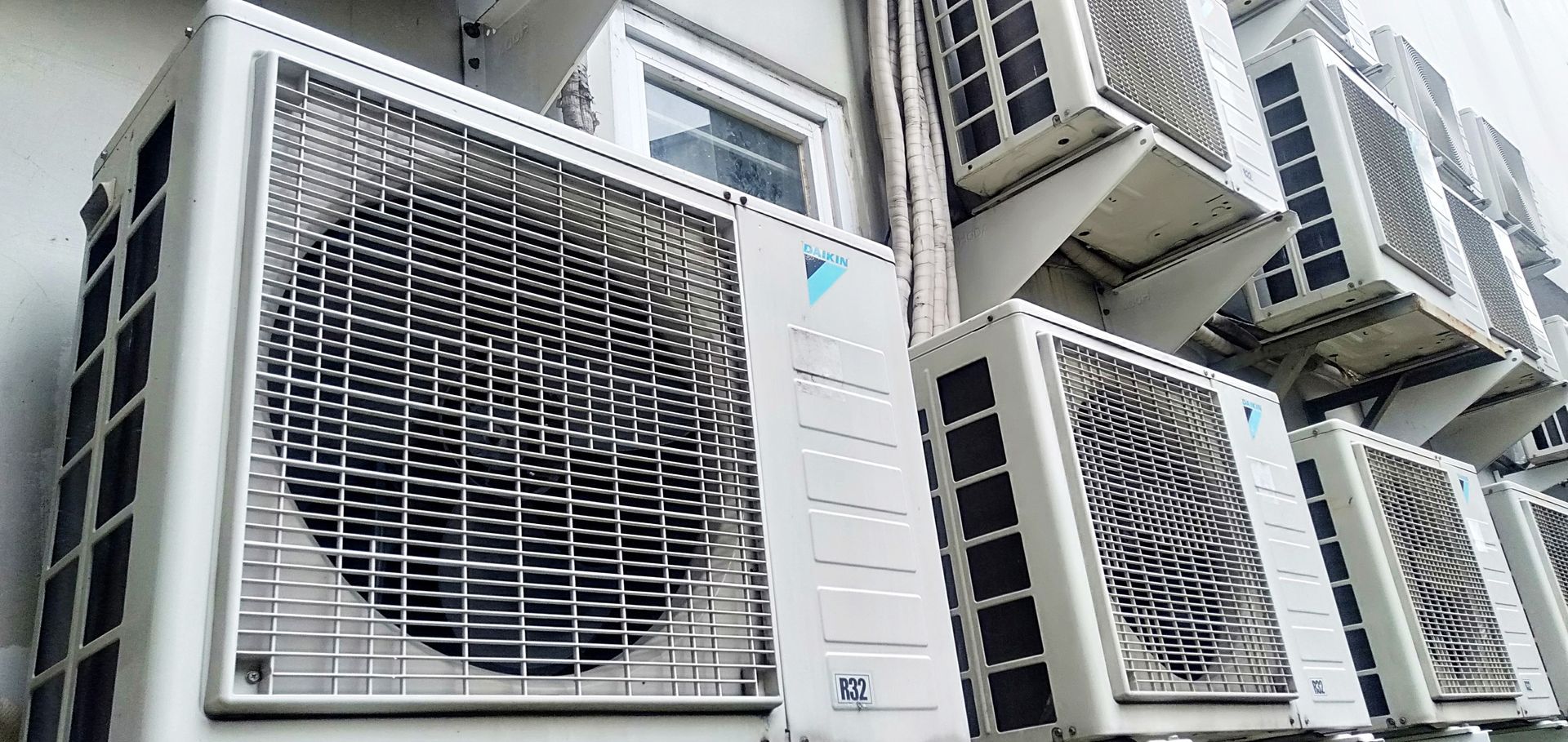 A row of air conditioners are stacked on top of each other on the side of a building.