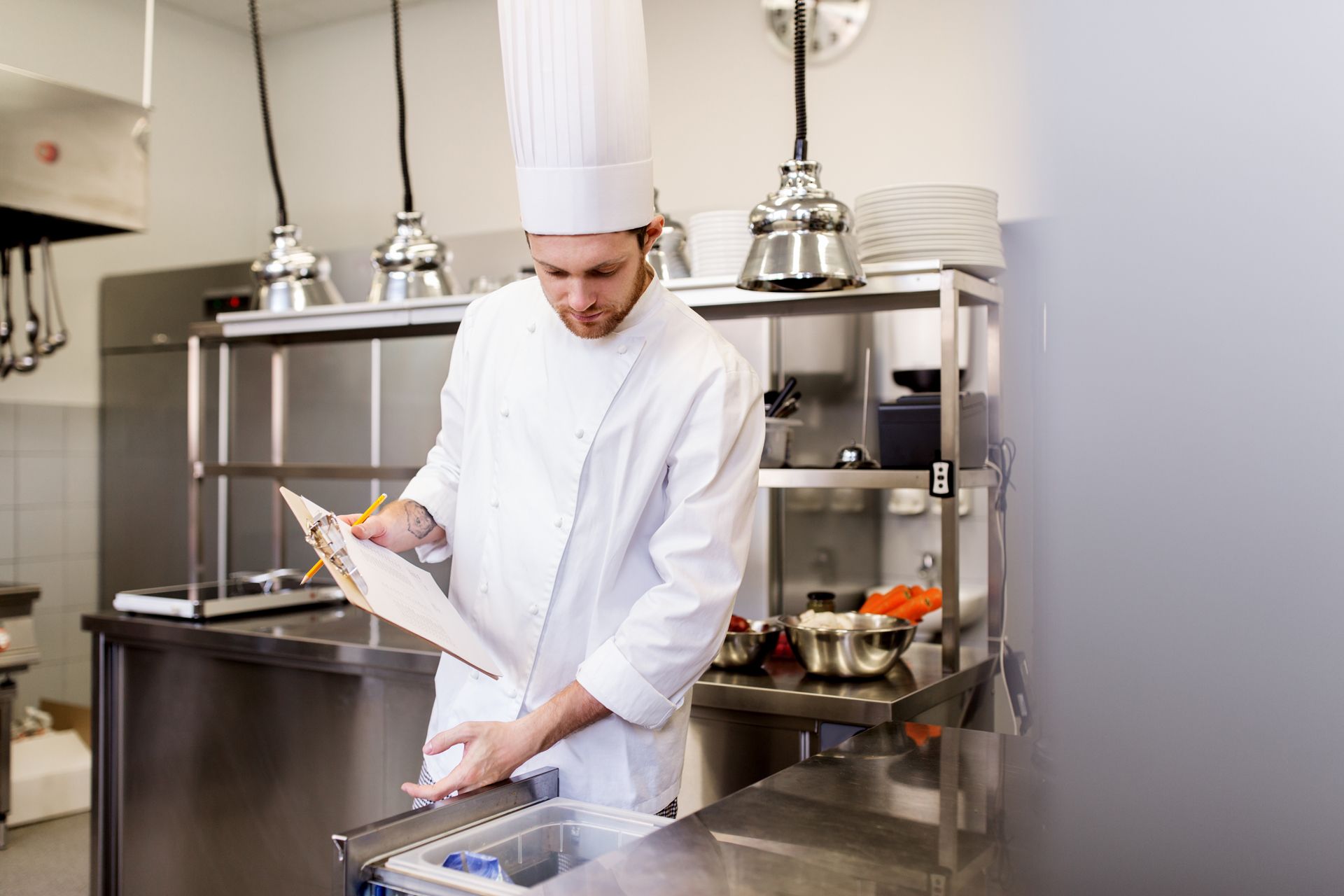 A chef is looking at a menu in a kitchen