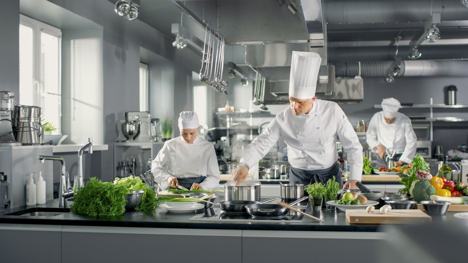 A group of chefs are preparing food in a commercial kitchen