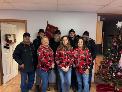 A group of people are posing for a picture in front of a christmas tree.