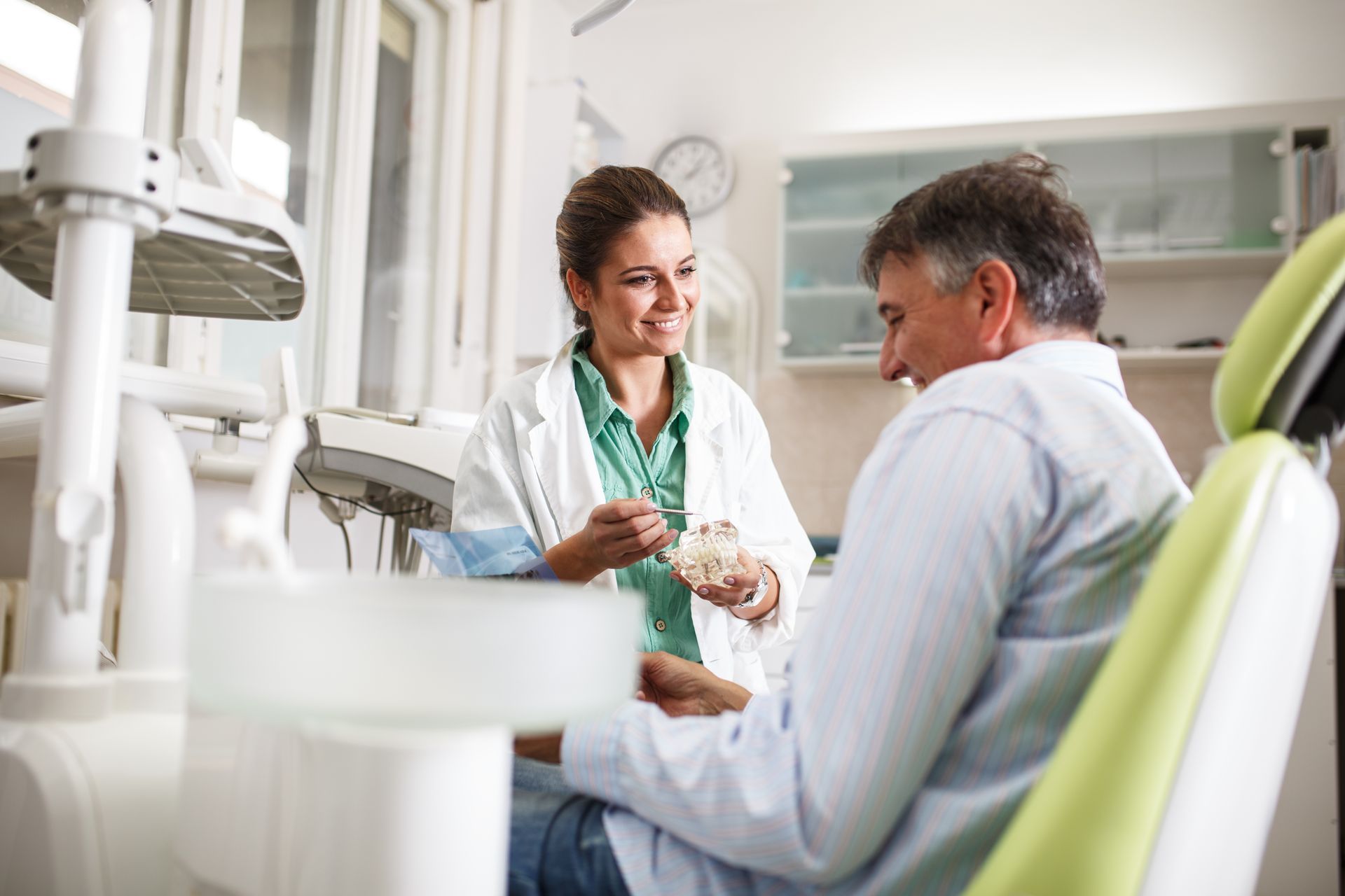 Dentist showing a dental model to a patient in a dental office.