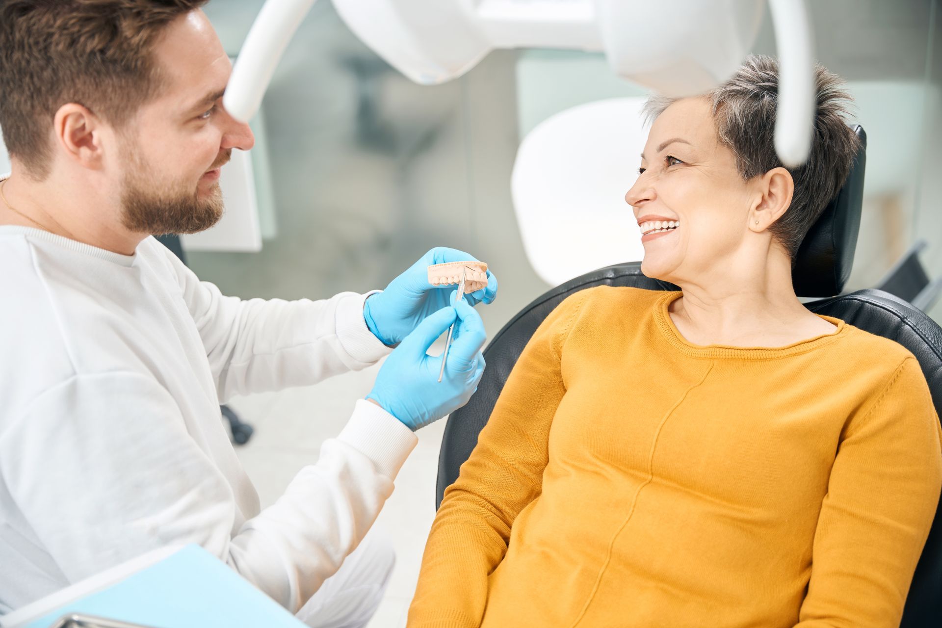 A woman is sitting in a dental chair talking to a dentist.