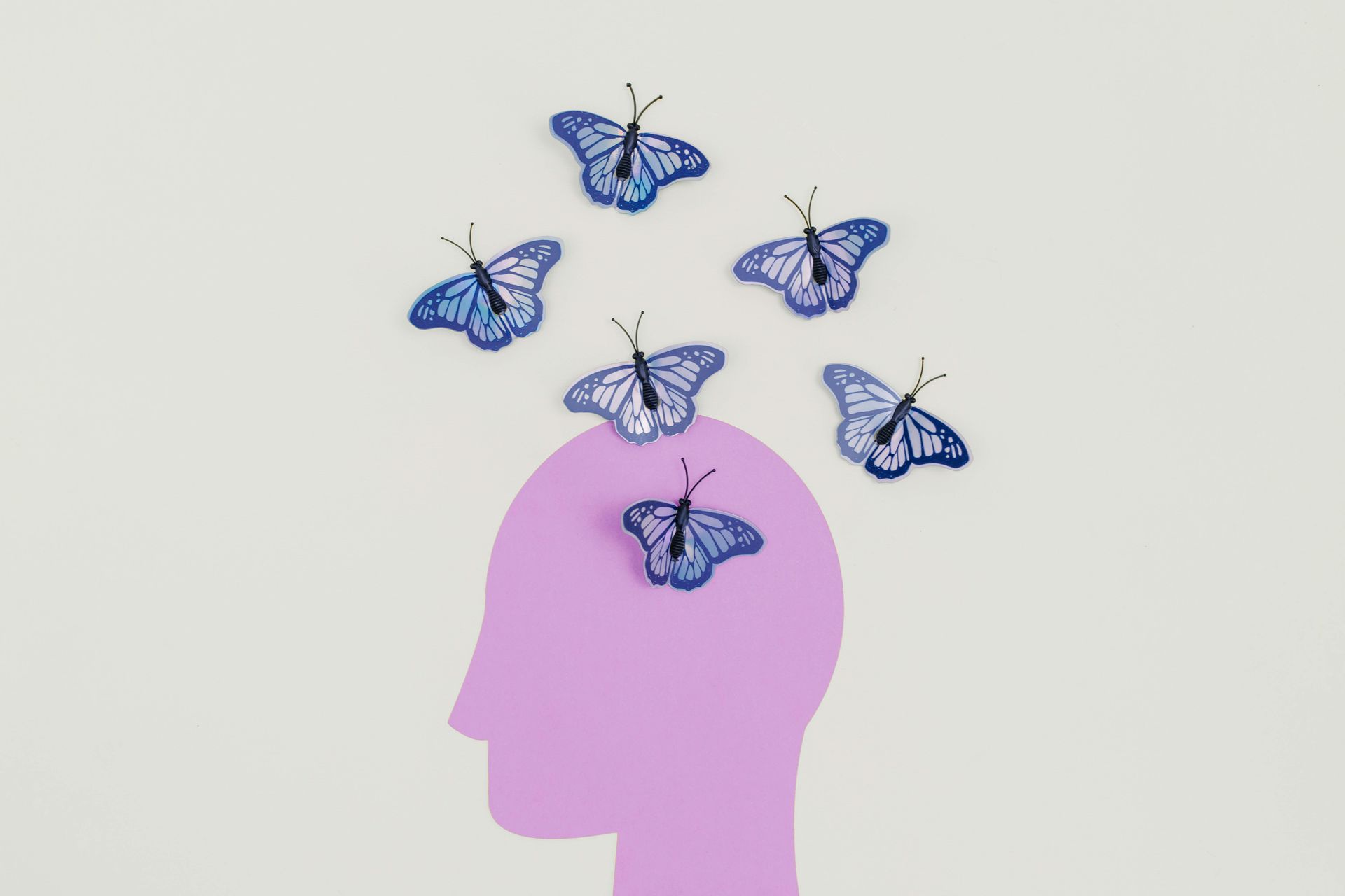 Purple head silhouette with blue butterflies above.
