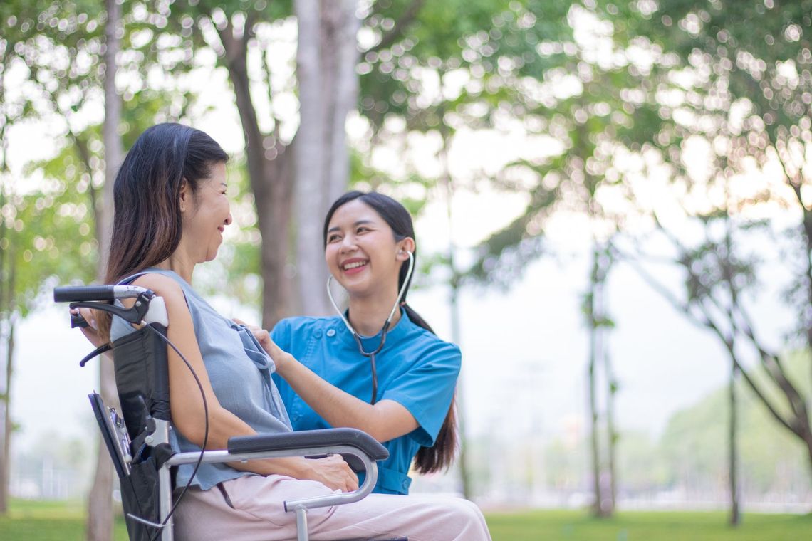 Two women smiling and talking on a bench in a sunny park