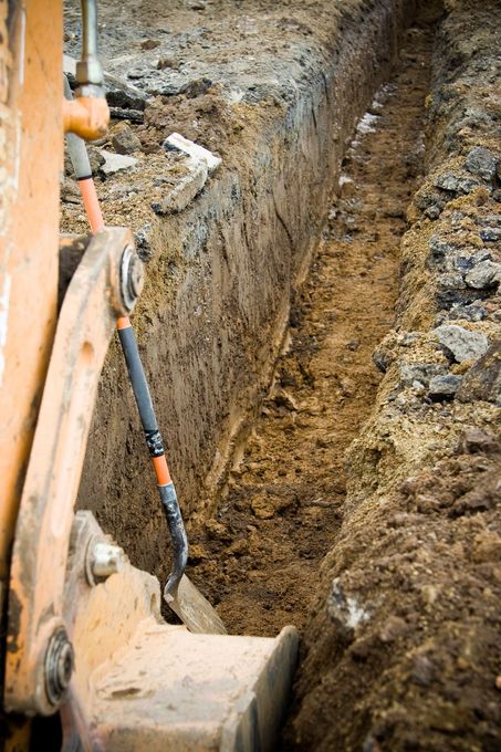 A construction vehicle is digging a trench in the ground.