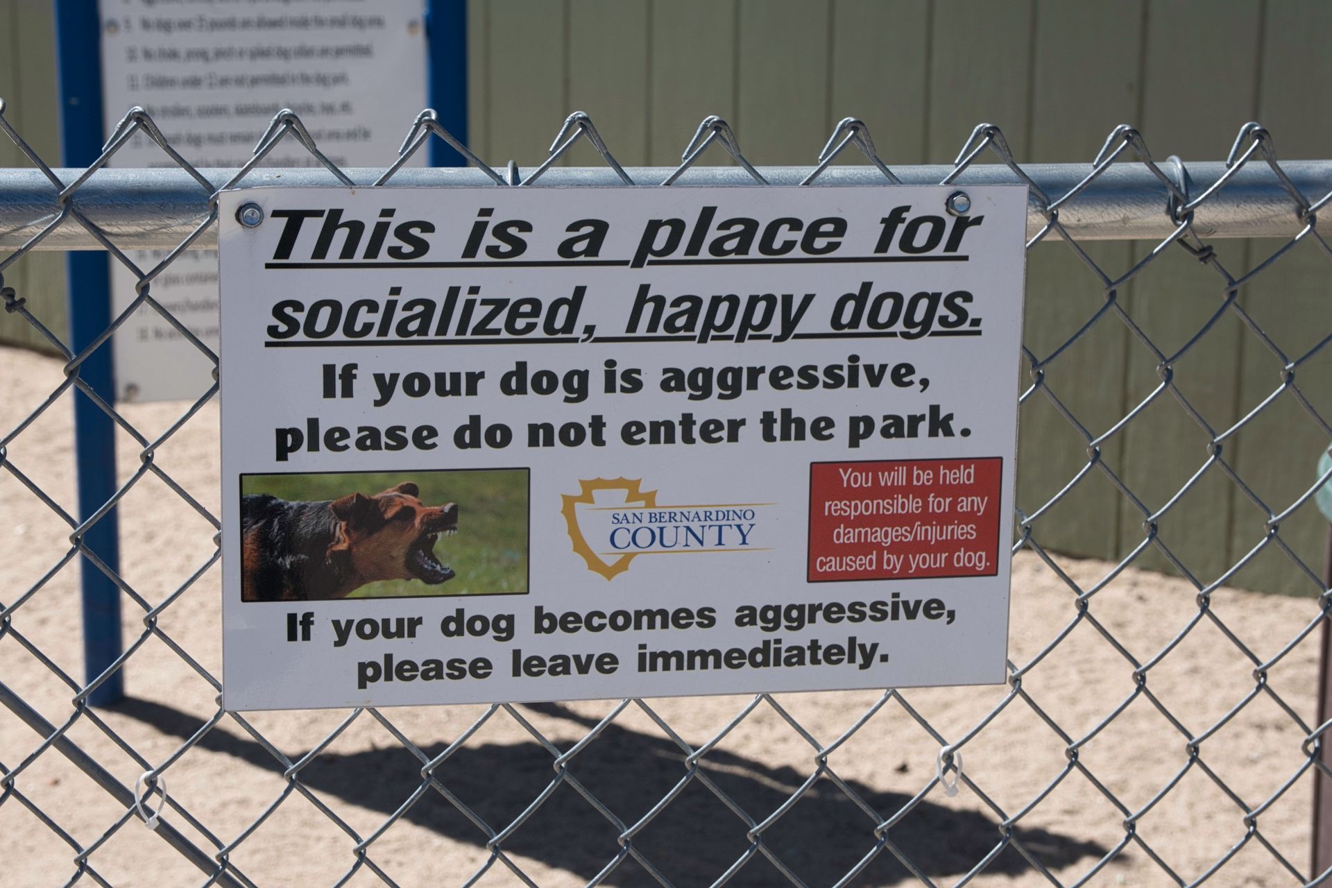 A sign on a chain link fence says this is a place for socialized happy dogs A sign on a chain link fence says this is a place for socialized happy dogs