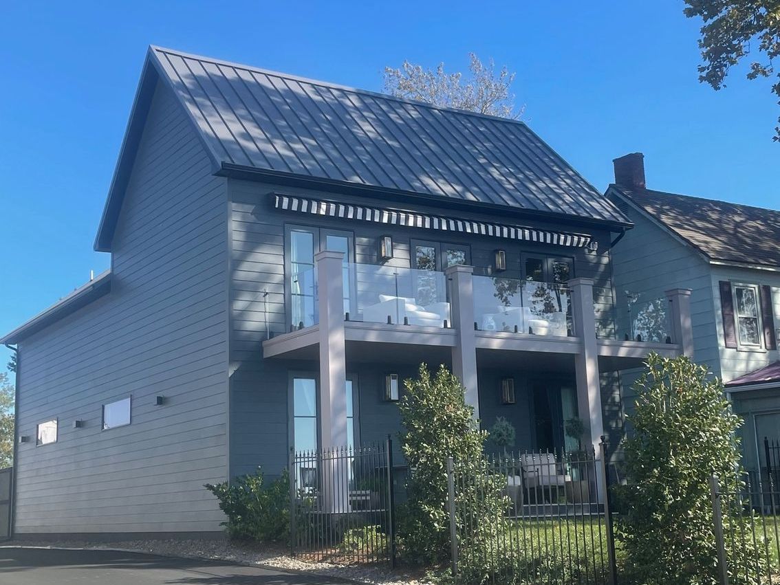 A 2-story house with a balcony and a metal roof