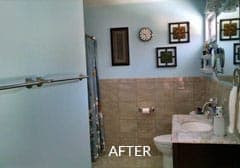 After view of a bathroom with a sink , toilet , shower and mirror.
