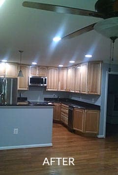 After renovation of a kitchen with wooden cabinets , stainless steel appliances , and a ceiling fan.