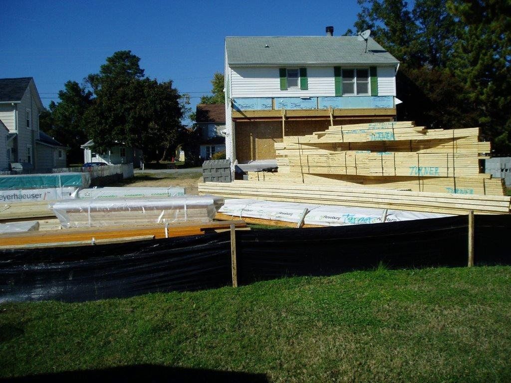 A stack of wood is sitting in front of a house under construction