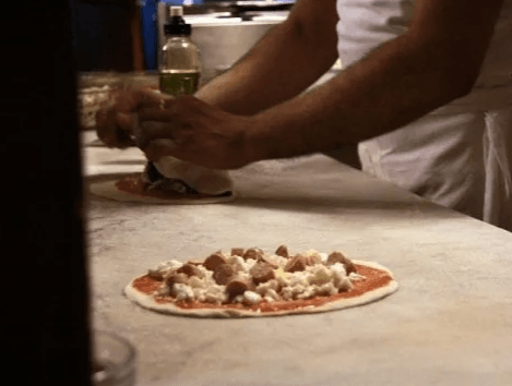 pizzaiolo che prepara le pizze con ingredienti genuini nella pizzeria sul mare a Bari