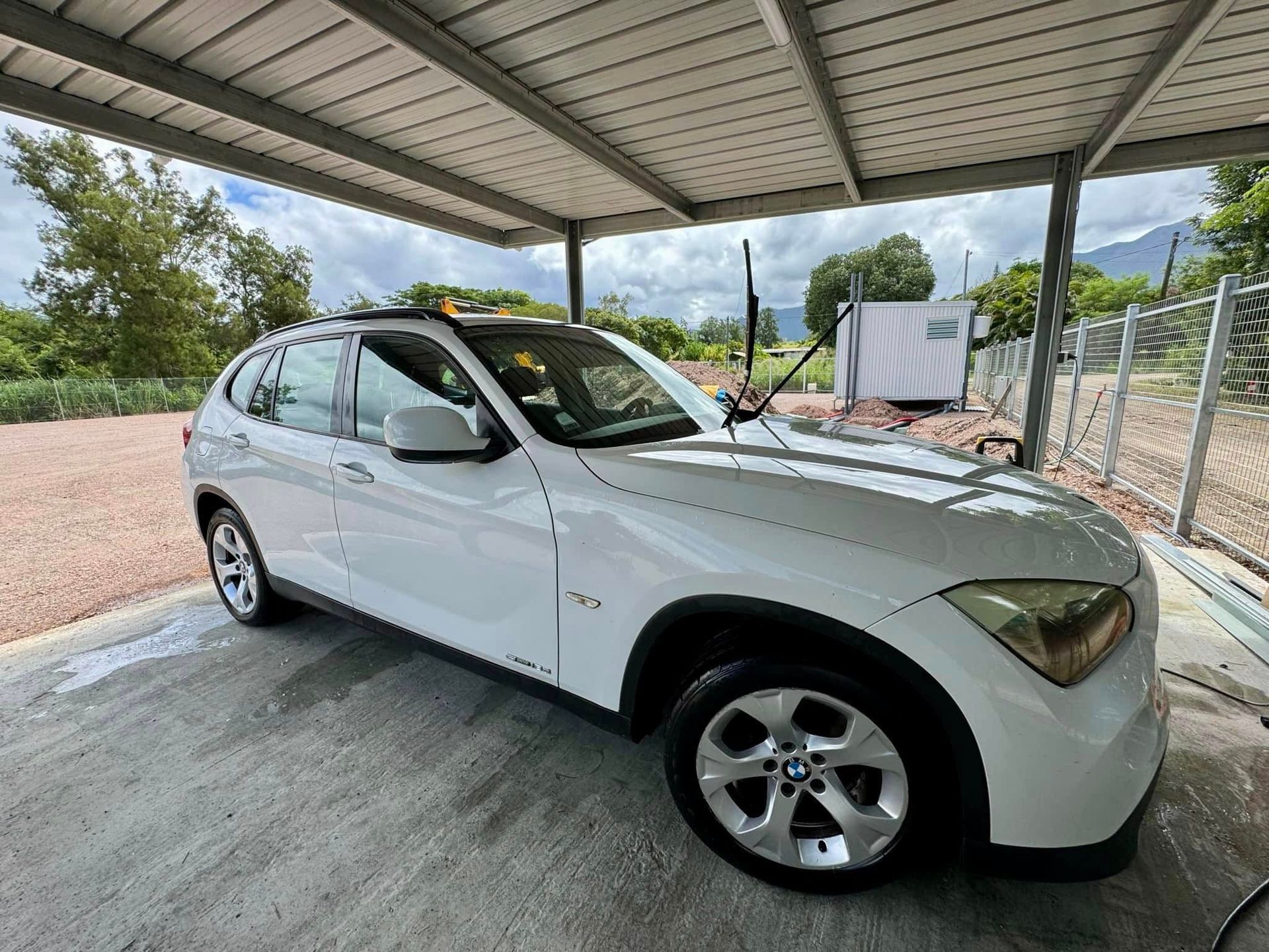 Voiture blanche stationnée sous abri sécurisé au parking Auto Safe Tontouta, avec service de lavage et gardiennage près de l’aéroport international de La Tontouta en Nouvelle-Calédonie